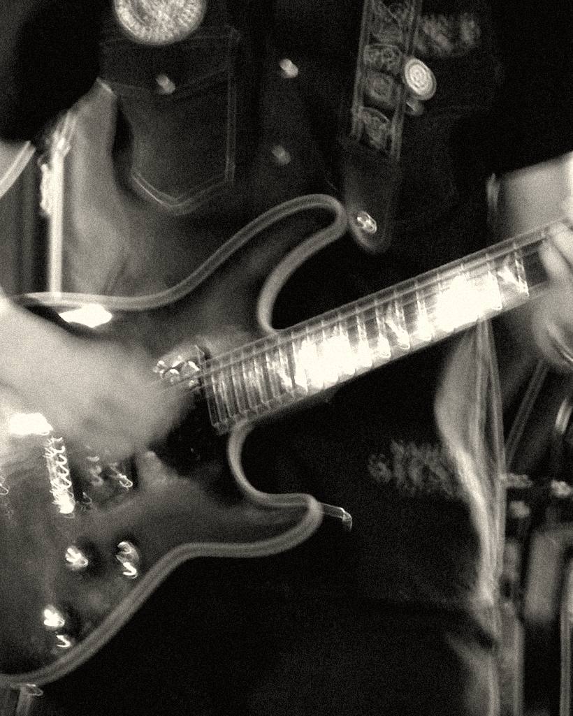 A guitarist's hands on the body of an electric guitar.